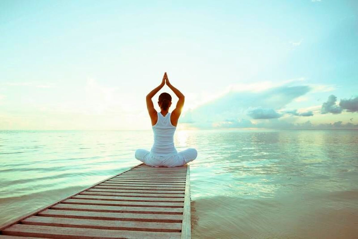 Frau auf einem Steg am See macht Yoga